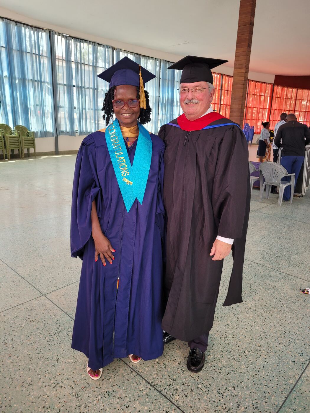 A graduate wearing a congratulations sash with Professor Mike