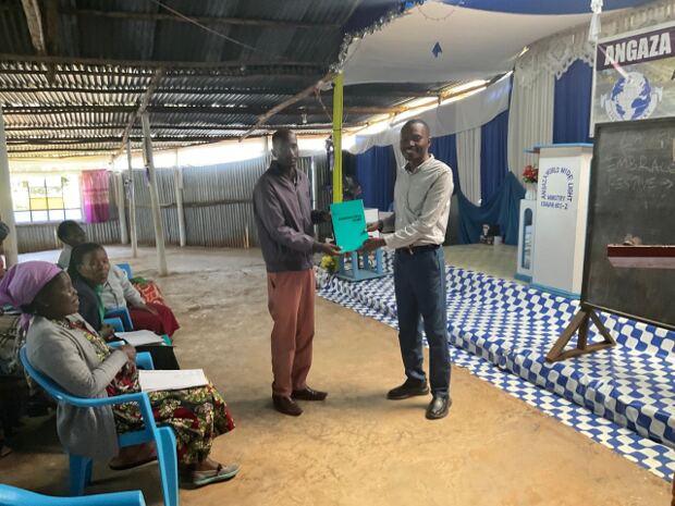 Pastor Allan presents a leadership training certificate to a church leader in Bomet, Kenya