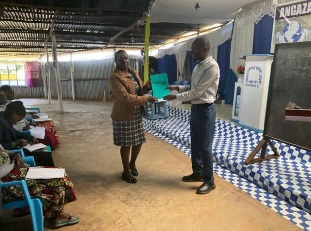 Pastor Allan presents a leadership training certificate to a female church leader in Bomet, Kenya